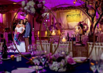a bride and groom taking a photo in the wedding hall, purple theme color
