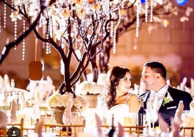 a bride and groom in a wedding ballroom under a decorated tree