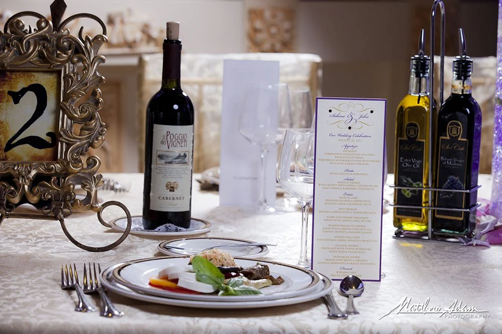 Wine tasting display with bottles, printed menus, and a small appetizer plate on a decorated table.